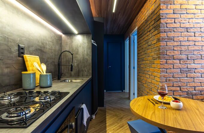 Apê de 39 m² tem cozinha azul, tijolos rústicos e quarto de hóspedes